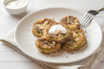 Fried zucchini slices in egg batter with garlic on a plate.