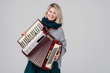 Pretty young happy woman with accordion. Playing music. Studio Shot. Over gray background