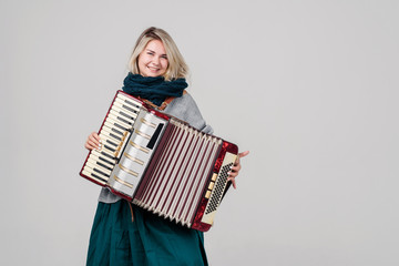 Pretty young happy woman with accordion. Playing music. Studio Shot. Over gray background
