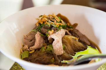 Asian pork noodle soup with beef meatball, pork and with fresh vegetable on dark wood table, street food, hot and spicy noodle soup, asian food. Close up noodles.Bangkok,Thailand.