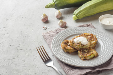 Fried zucchini slices in egg batter with garlic on a plate.