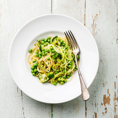 Courgetti Spaghetti Pasta with zucchini, broccoli and green pea on plate on blue wooden background