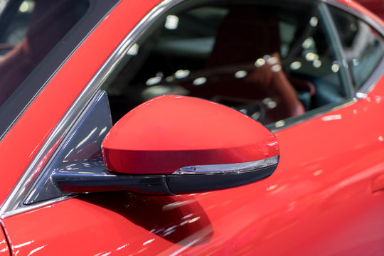 Red side view mirror with red sport modern car.
