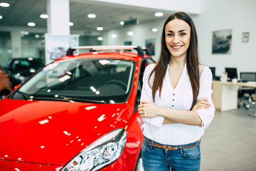 Smiling young beautiful woman in dealership. Beautiful woman buying a new car for job and travel in dealership, girl customer