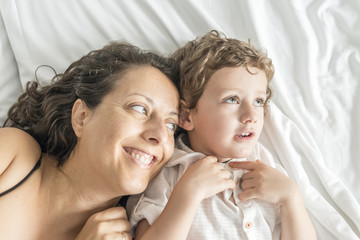 A woman and her son playing in bed.