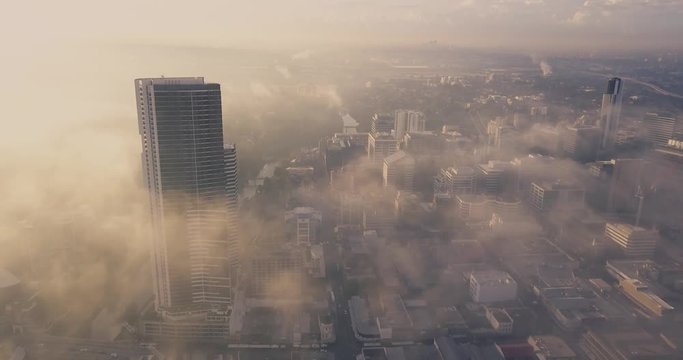 Drone aerial fly over. Sunrise and misty foggy morning over a metropolis, metropolitan down ton city precinct.