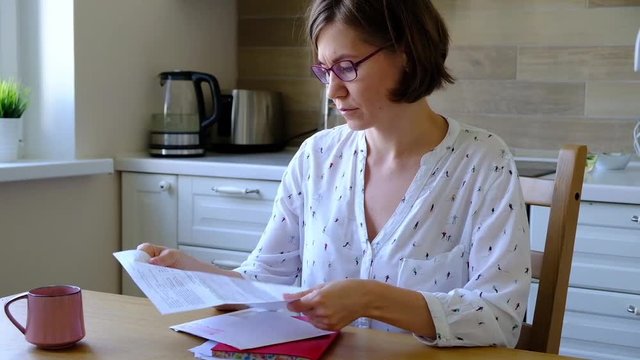 Stressed over bills. Unpset woman looking at her financial debts in the kitchen.