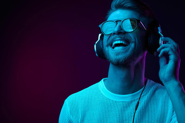 Neon portrait of bearded smiling man in headphones, sunglasses, white t-shirt. Listening to music - 216136125