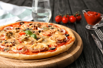 Board with tasty pizza on wooden table, closeup