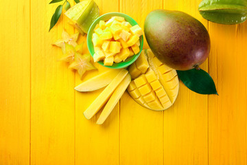 Composition with fresh mango on color wooden background