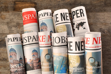 Rolled newspapers on wooden background