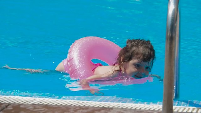 Happy child in the pool. A little girl is swimming in an inflatable circle.