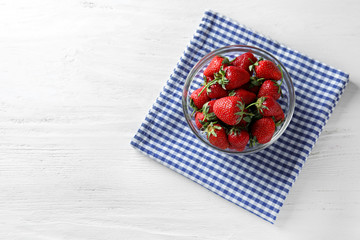 Glass bowl with sweet ripe strawberries on white wooden table
