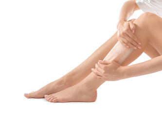 Young woman epilating her legs with wax on white background