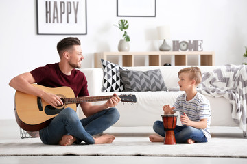 Little boy and his dad with music instruments playing at home