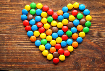 Heart made of colorful candies on wooden background