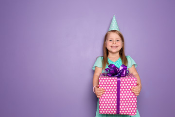 Cute little girl with gift for her birthday on color background