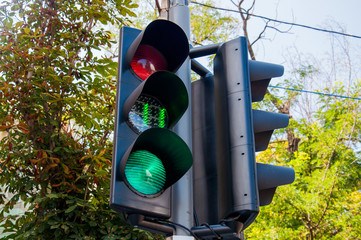 Black traffic lights showing a green color light in the city with a timer showing the seconds....