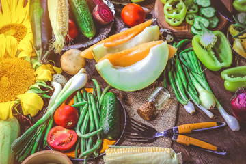 melon slices and various summer and autumn vegetables and food for cooking on a wooden table.