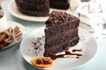 Plate with piece of delicious chocolate cake on light table