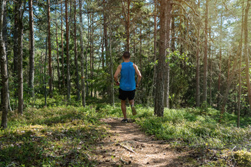 Fototapeta premium Man running along a trail in a forest, outdoor trailrunning