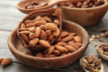 Bowl with fresh tasty almonds on wooden table