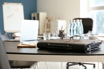 Briefcase with eyeglasses on table prepared for business meeting in conference hall