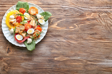 Plate with tasty chicken salad on wooden table