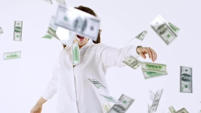 Studio shot with white background: ecstatic woman in white shirt laughing and flailing her arms as cash money flying towards her
