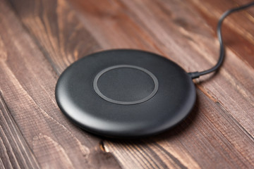 Wireless charger for mobile phone on a wooden brown background