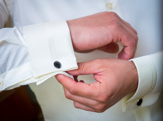 Men's hands. The man fastens buttons on his sleeves.
