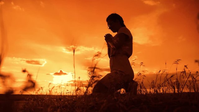 the girl prays. Girl folded her hands in prayer silhouette at sunset. slow motion video. Girl folded her hands in prayer pray to God. girl praying asks forgiveness for sins of lifestyle repentance