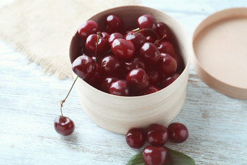 Box with tasty ripe cherries on wooden background