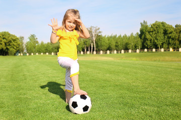 Cute little girl playing football in park on sunny day