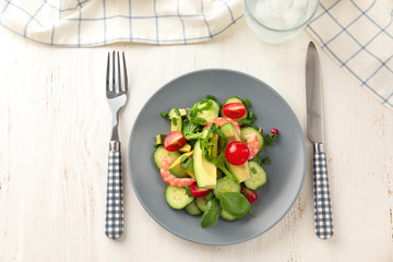 Plate with tasty avocado salad on table