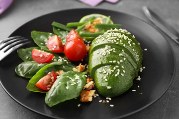 Plate with tasty avocado salad on table, closeup