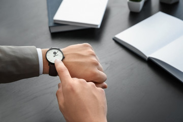 Businessman looking at his watch indoors. Time management concept