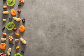 Various nuts and dried fruits on grey textured background
