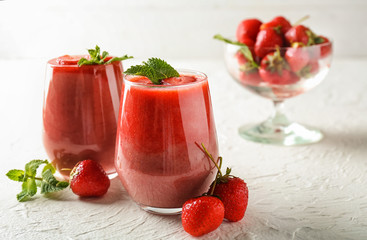 Glasses with strawberry smoothie on light textured background