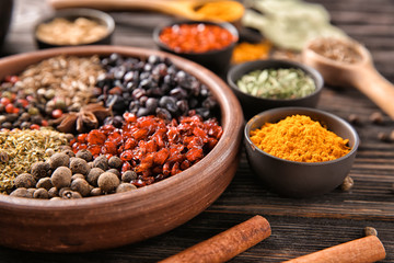 Bowls with different dry spices on wooden background