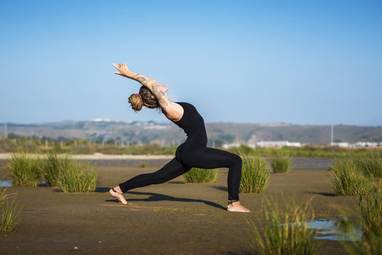 Woman on Los Lances beach doing warrior I yoga pose, The Strait Natural Park, Tarifa, Cadiz, Andalusia, Spain