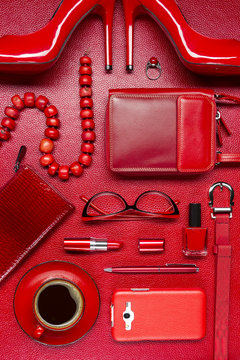 Woman red accessories with coffee, cosmetic, jewelry, shoes, gadget and other luxury objects on leather background, fashion industry, modern female concept 