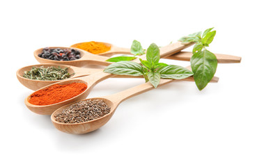 Wooden spoons with different spices on white background