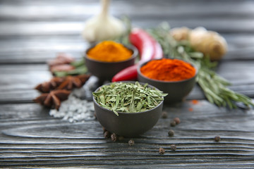 Bowls with different spices on wooden background