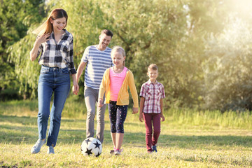 Family playing football in park on summer day