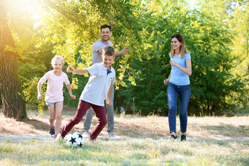 Happy family playing football outdoors