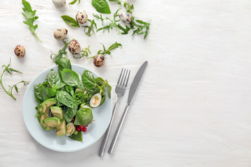 Plate with tasty avocado salad on white wooden table