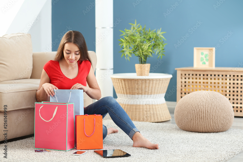 Sticker Young woman looking into shopping bag at home