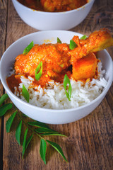 Curry chicken with rice served in a bowl over wooden background.