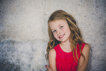 beautiful girl in red shirt in front of concrete background is posing and pointing